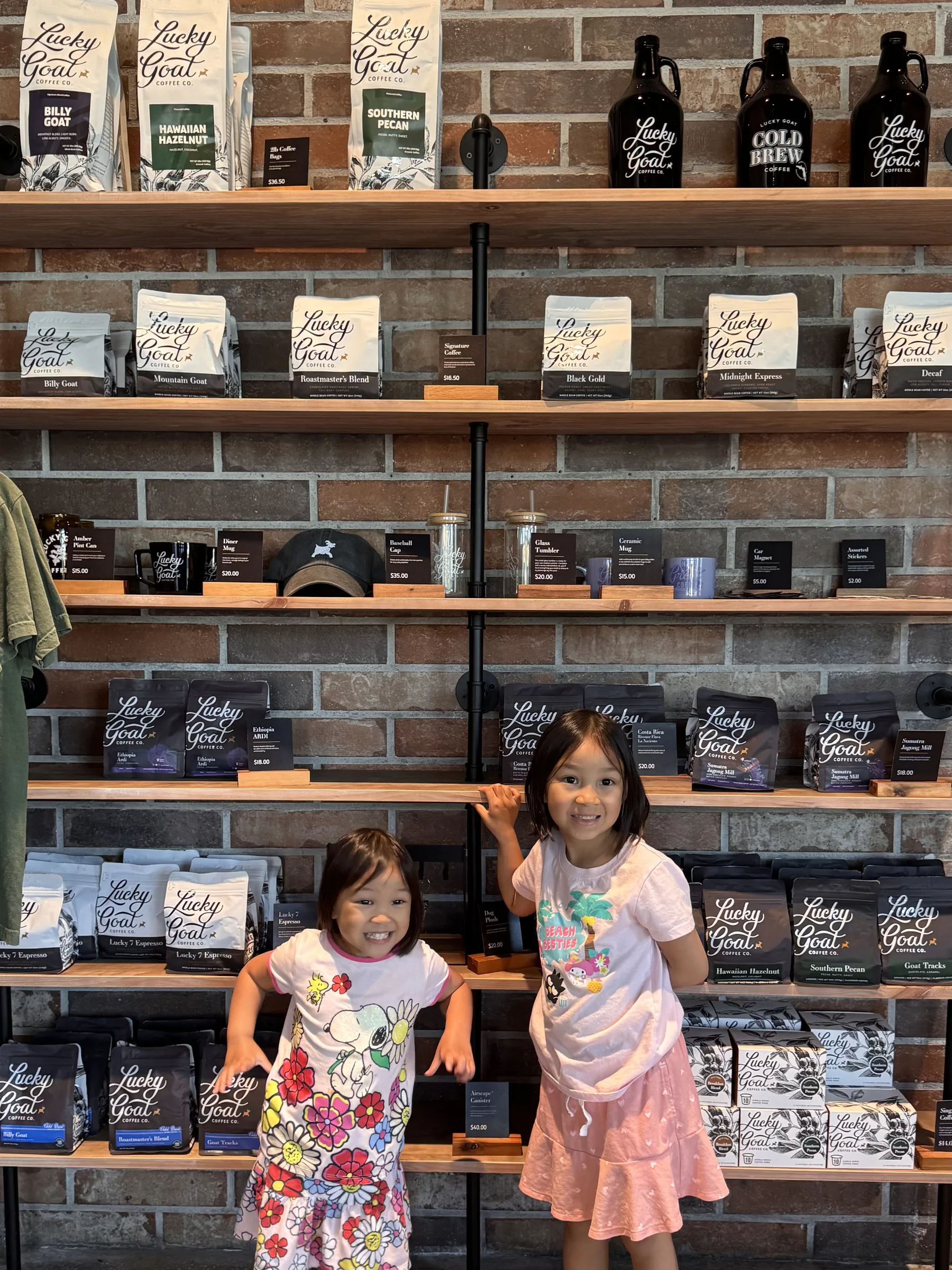Claire and Emily smiling in front of the merchandise and coffee shelves at Lucky Goat in Jacksonville